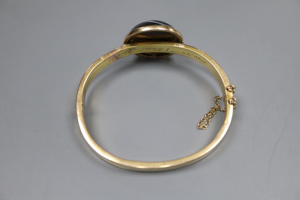 An early 20th century yellow metal (stamped 15) and banded agate set hinged bangle (repaired) and a Victorian mourning brooch.